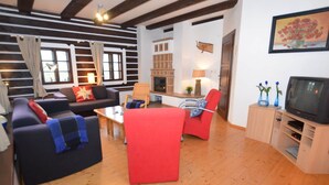 A living room with a fireplace, a television, and a dining area. - Luxury Chalet in Stupna near Ski Area (Vidochov)