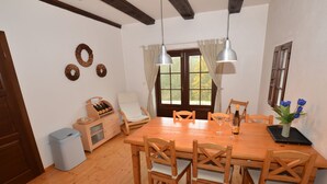 A dining area with a wooden table, six chairs, two pendant lights, a wine bottle, and a vase with flowers. - Luxury Chalet in Stupna near Ski Area (Vidochov)