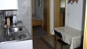 A compact kitchen with a stove, sink, and a small dining table. - Charmantes Apartment in Jennewitz, in Ostseenahe (Kroepelin)