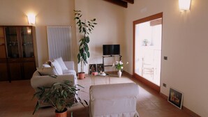 Un salon avec un canapé, une table basse, un téléviseur et des plantes en pot.