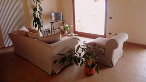 Un salon avec un canapé, une table basse, un téléviseur et une plante en pot.