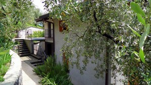 Un bâtiment doté d’un escalier menant à un balcon, le tout entouré de verdure.