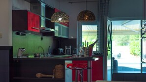 Une cuisine moderne avec un îlot central, des tabourets de bar rouges et des luminaires suspendus.
