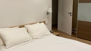 Une chambre d’hôtel avec un lit, une table de chevet, une lampe et une armoire.