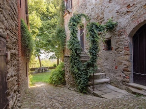 A narrow cobblestone alley with stone walls, a wooden door, and a staircase leading to a second level. - Guest House in Monferrato With Wine Tasting (Tagliolo Monferrato)