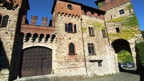 Un edifici de pedra històric amb una porta de fusta gran, finestres arquejades i una torre amb rellotge.