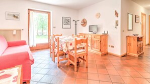 A cozy room with a dining table, chairs, a pink sofa, a wooden cabinet, and a radiator. - Spacious Chalet with Garden near Ski Area in Tyrol (San Giovanni di Fassa)