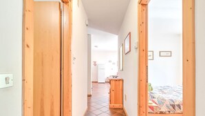 A narrow hallway with wooden doors leading to a bedroom with a bed and a small desk. - Spacious Chalet with Garden near Ski Area in Tyrol (San Giovanni di Fassa)