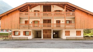 A two-story wooden building with a balcony, a wooden fence, and a gravel driveway. - Spacious Chalet with Garden near Ski Area in Tyrol (San Giovanni di Fassa)