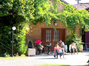 A brick building with a door and windows, surrounded by greenery and outdoor seating. - Countryside Bliss With Pool & Tennis (Pontecchio Polesine)
