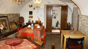 Zona pranzo con tavolo apparecchiato per due, un lampadario e una parete in pietra.