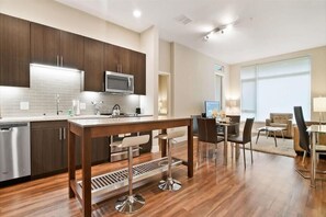 Enjoy meals in the kitchen with oven, microwave, and dishwasher, and dine in the adjacent area with a wooden table and comfortable seating.