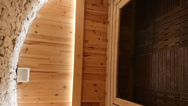 Un interior de fusta amb sostre inclinat, una finestra i un radiador.