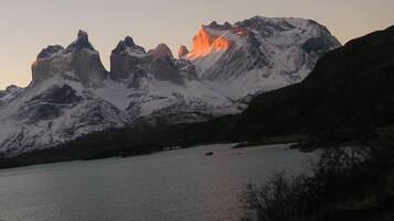 A mountain range with snow-covered peaks and a calm lake in the foreground.