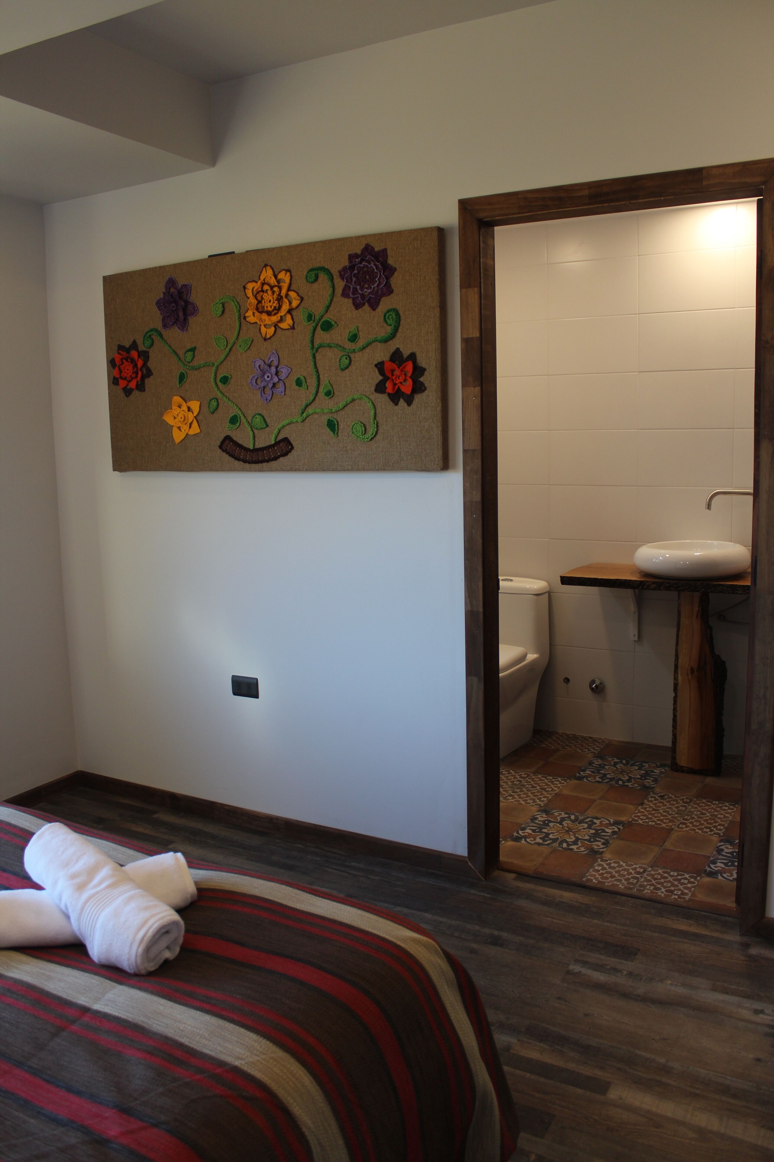 A hotel room with a bed, a bathroom with a sink and toilet, and a wall decoration.