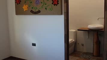 A hotel room with a bed, a bathroom with a sink and toilet, and a wall decoration.