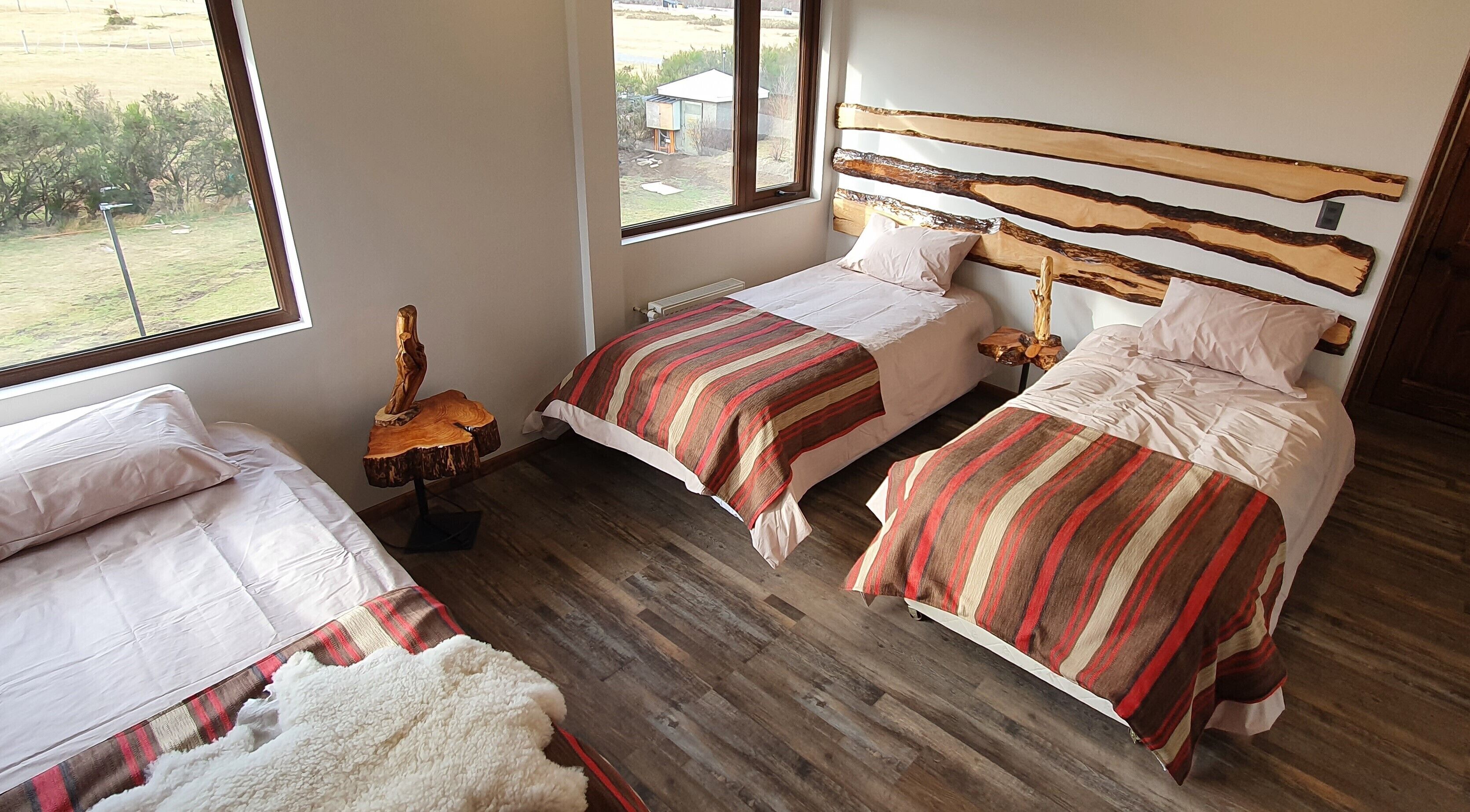 A bedroom with two beds, a wooden headboard, and a view of the outdoors.