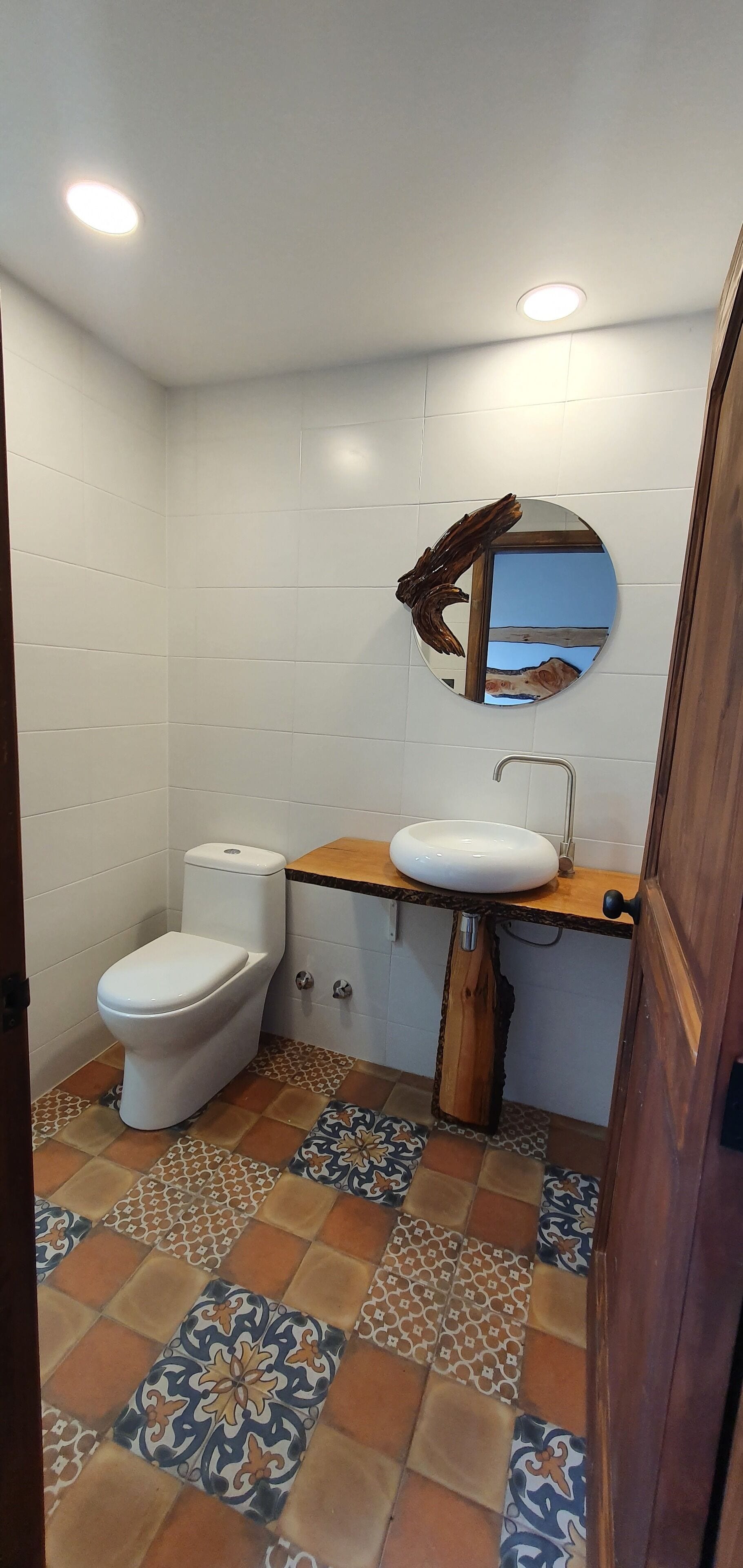 A bathroom with a toilet, sink, and mirror.