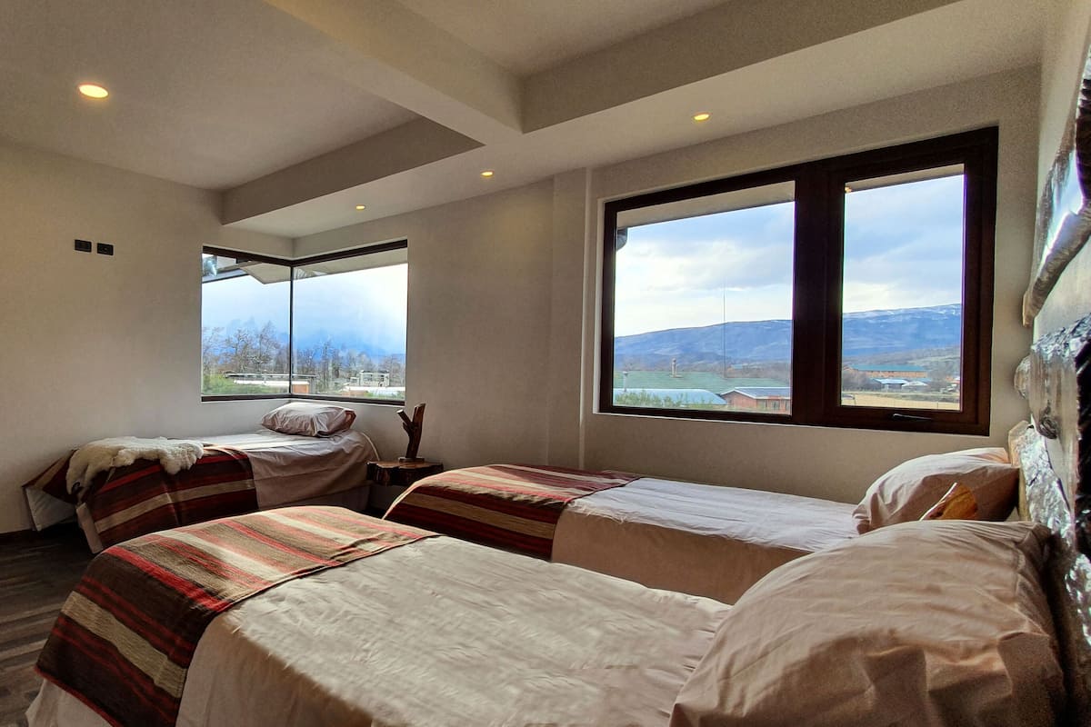 Ein Hotelzimmer mit zwei Betten, einem großen Fenster mit Bergblick und Holzboden.