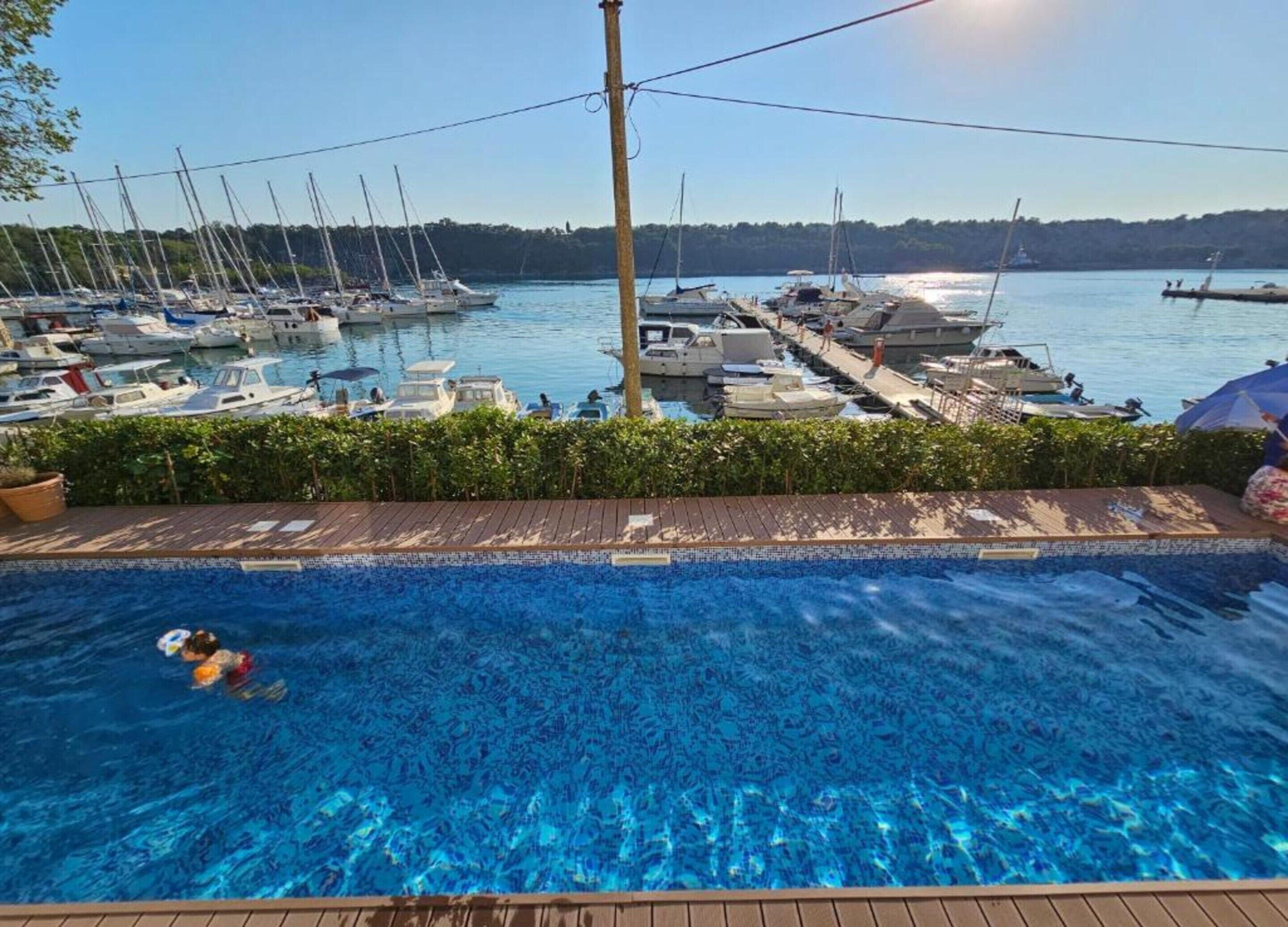 Una piscina con vista a barcos amarrados en un puerto deportivo.
