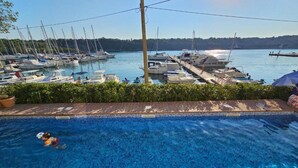 En swimmingpool med utsikt över båtar som ligger förtöjda i en småbåtshamn.