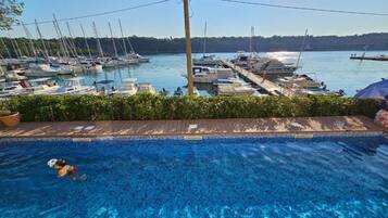 Una piscina con vista a barcos amarrados en un puerto deportivo.