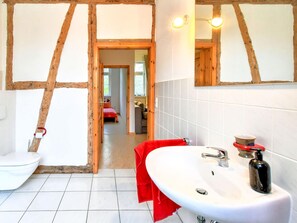A bathroom with a white sink, a mirror, and wooden beams on the ceiling.