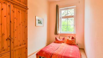 Ein Schlafzimmer mit einem Bett, einem Fenster und einem Holzschrank.