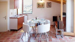 Un comedor con una mesa redonda, sillas blancas y un ventanal con vistas a árboles.