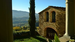 A stone building with an arched entrance and a window, surrounded by greenery and mountains in the background. - Peaceful Farmhouse in Dicomano (Dicomano)