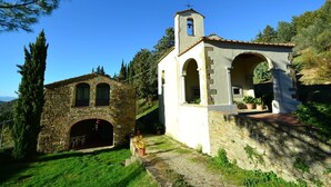 A stone church with a bell tower and an arched entrance, surrounded by greenery and a clear blue sky. - Peaceful Farmhouse in Dicomano (Dicomano)