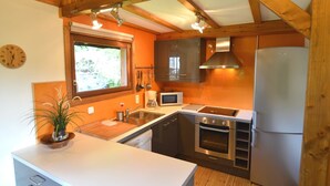 A kitchen with wooden beams, a sink, a stove, a microwave, and a refrigerator. - Pretty Cottage Ardennes near Valley of Lesse & Semois (Gedinne)