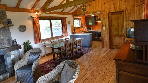 A rustic cabin interior with a dining area, kitchen, and a stone fireplace. - Pretty Cottage Ardennes near Valley of Lesse & Semois (Gedinne)