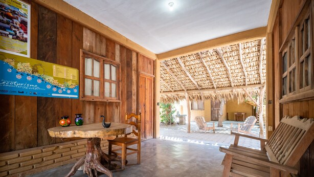 A wooden interior with a table and chairs, a map on the wall, and a thatched roof structure. - OYO Cabañas Abril, Mazunte (Santa María Tonameca)