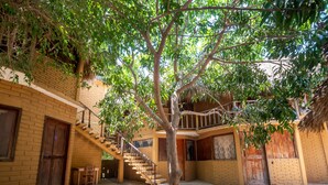 A courtyard with a staircase leading to an upper level, surrounded by brick walls and a tree providing shade. - OYO Cabañas Abril, Mazunte (Santa María Tonameca)