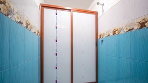 A bathroom with blue tiled walls, a wooden-framed door, and a tiled floor. - OYO Cabañas Abril, Mazunte (Santa María Tonameca)