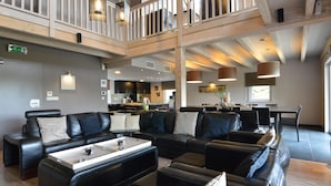 A spacious lounge area with leather sofas, a coffee table, and pendant lighting. - Luxurious Villa in Nadrin Belgium with Sauna & Hot Tub (Houffalize)
