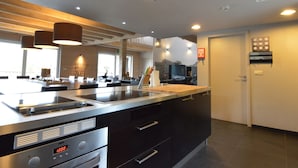 A modern kitchen with a large island, built-in appliances, and pendant lighting. - Luxurious Villa in Nadrin Belgium with Sauna & Hot Tub (Houffalize)
