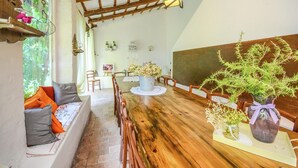 A dining area with a wooden table, chairs, and a bench. There are potted plants on the table and a window with curtains. - Cottage in Montefiore Near Forest and Beach (Montefiore Conca)