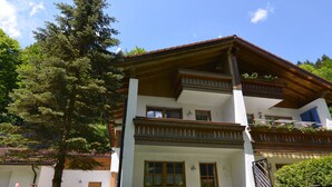Uma casa de dois andares com varanda, escorrega e um pátio com móveis de exterior.