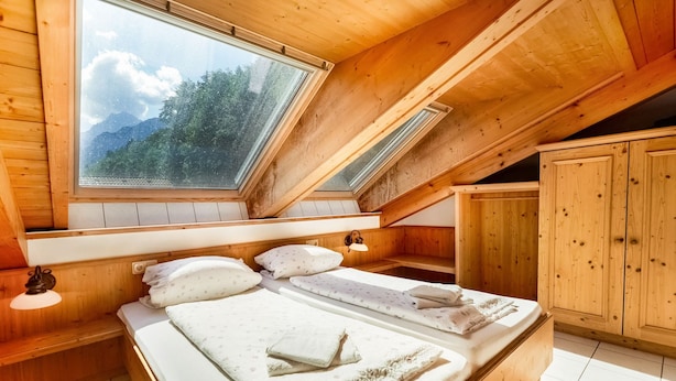 Quarto de cabana de madeira com duas camas, um claraboia e um guarda-roupa de madeira.