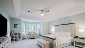 A bedroom with a bed, a ceiling fan, a window with blinds, a bookshelf, and a television. - 4 Lark Street - 4th Row North Forest Beach (Hilton Head Island)
