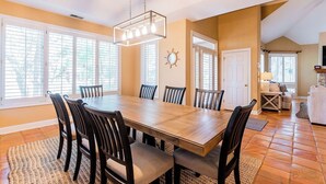 A dining area with a wooden table and chairs, large windows, and a chandelier. - 4 Lark Street - 4th Row North Forest Beach (Hilton Head Island)