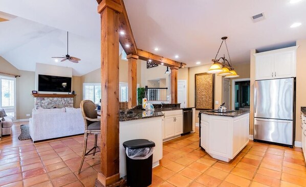 Modern kitchen with island, seating area, and stainless steel appliances.
