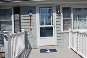 Stylish exterior with a white door, glass panel, and small porch area.