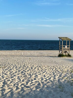 Een zandstrand met een houten redderstribune en de oceaan op de achtergrond.