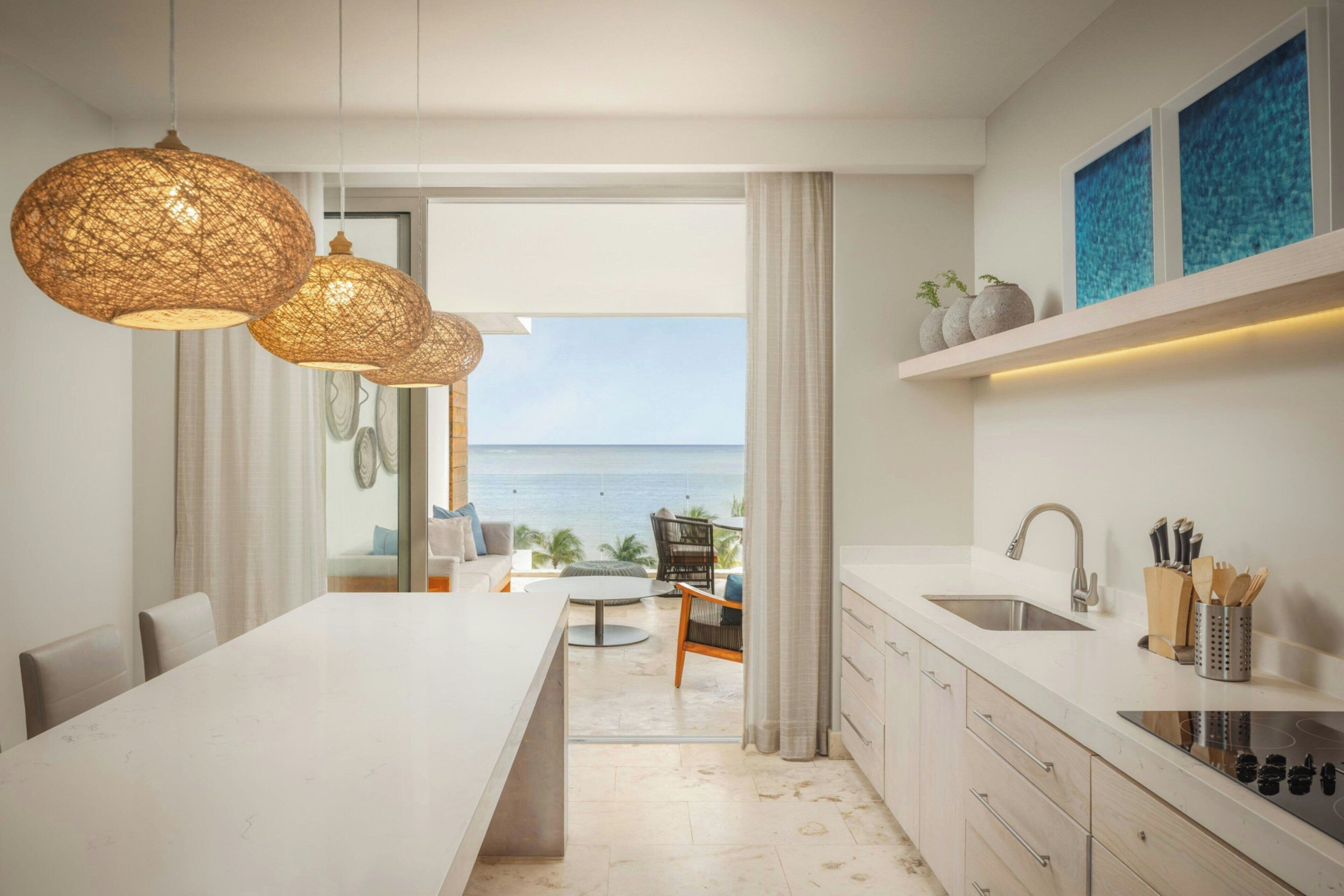 A modern kitchen with a view of the sea, a dining area, and a kitchen island.