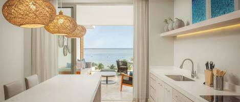 A modern kitchen with a view of the sea, a dining area, and a kitchen island.