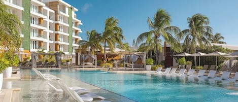A resort pool with clear water, lounge chairs, and palm trees.