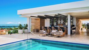 Un área de piscina en la azotea con bar y asientos, con vistas a un paisaje urbano.